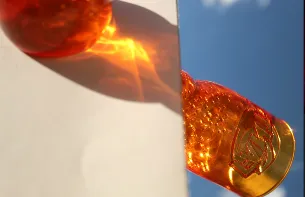 An orange glass casting a coloured shadow